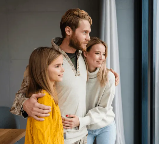 Familia de propietarios mirando por la ventana de su casa