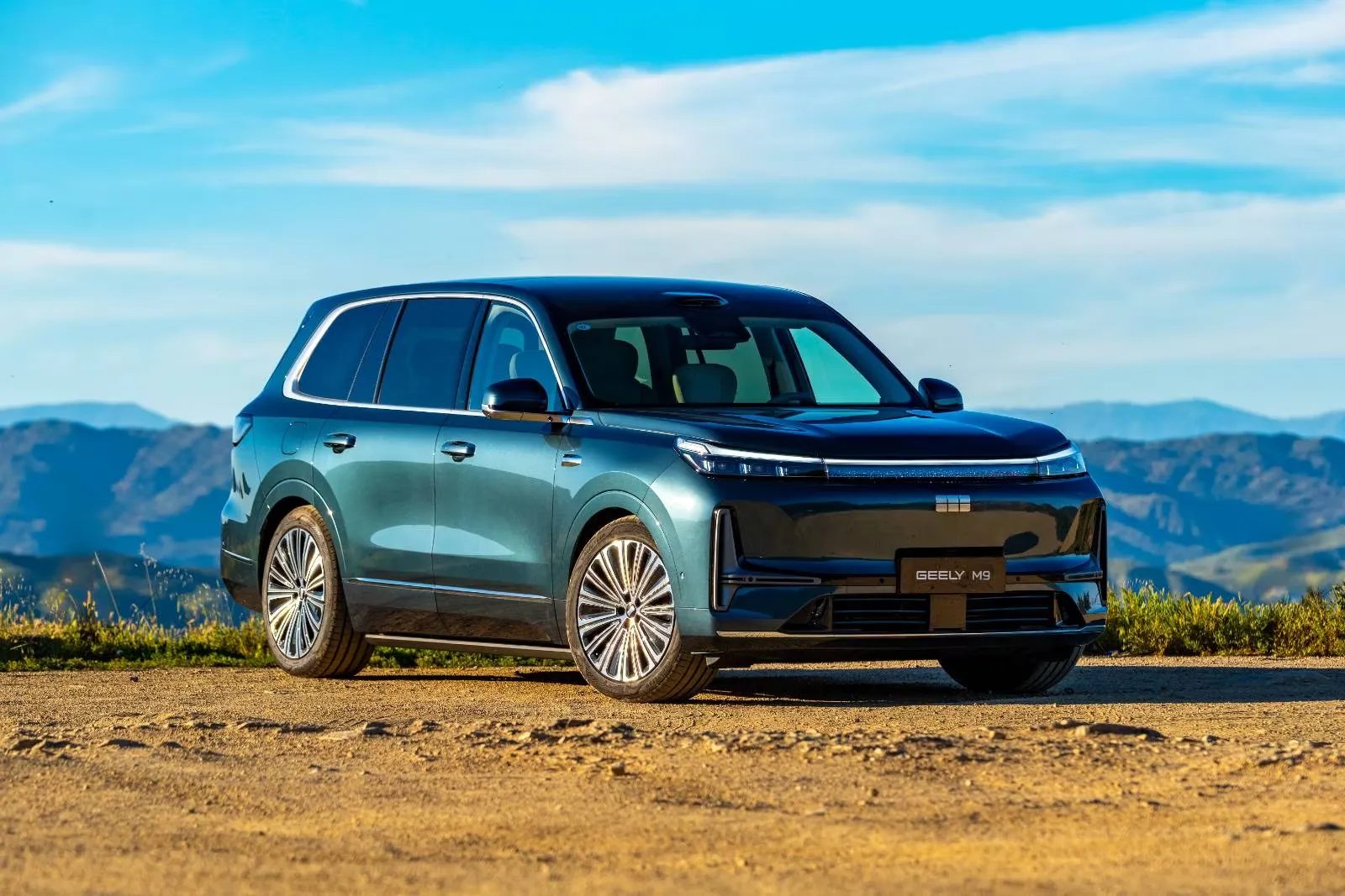 SUV Geely M9, auto de marca china, frente a un paisaje de montañas